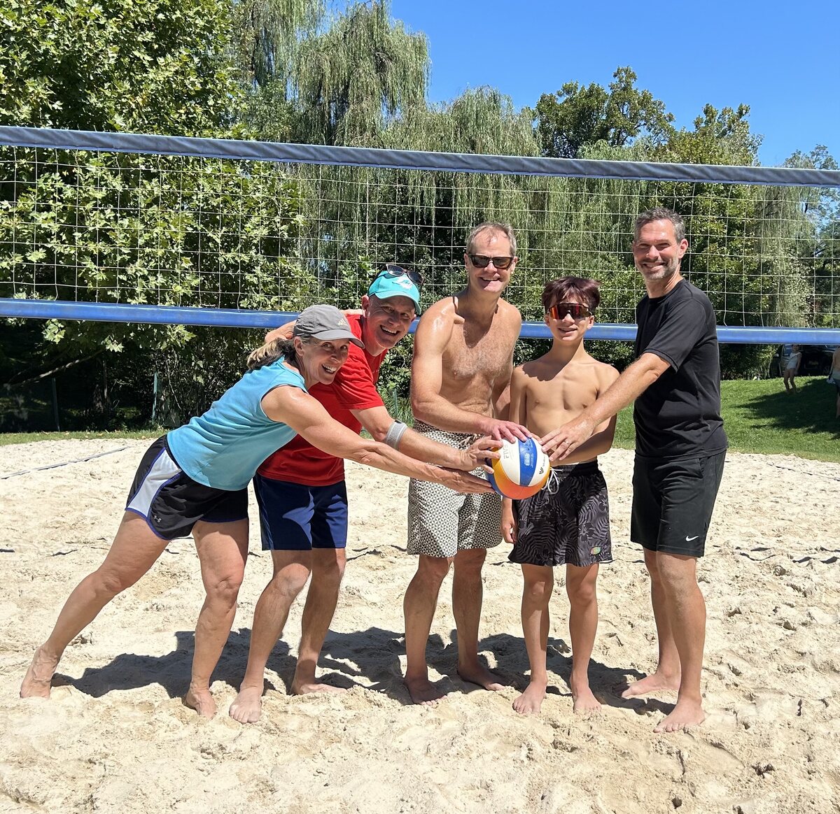 A volleyball team posing with the ball at the net
